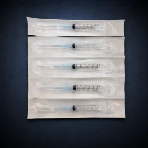 Five sterile 3 mL Luer-lock syringes with attached 23G needles on a dark navy background